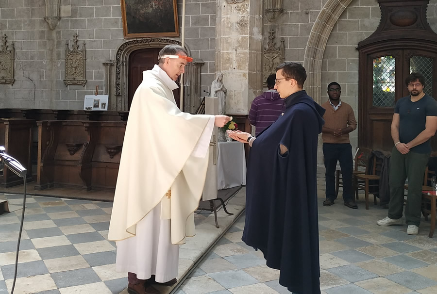 Un père du séminaire donnant la communion à un séminariste au moment du déconfinement